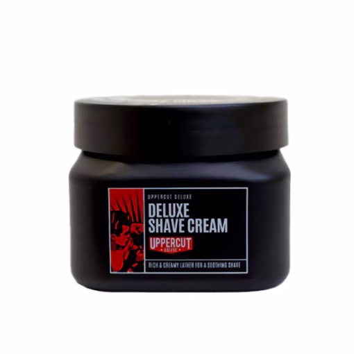 UPPERCUT - Deluxe Shave Cream 120g Uppercut Deluxe Shave Cream 120g é a escolha perfeita para quem valoriza uma experiência de barbear confortável, profunda e especialmente pensada para peles sensíveis ou secas. Assim que começas a preparar, a fórmula transforma-se rapidamente numa espuma cremosa, criando um manto protetor que facilita o deslizar da lâmina e ajuda a prevenir cortes ou irritações, deixando sempre a pele mais macia e saudável. Família sensorial: Fresca e delicada, esta shave cream destaca-se pela textura suave e envolvente da espuma, que amacia a pele e garante uma sensação de hidratação profunda durante e após o barbear. Não possui perfumes intrusivos, tornando-se perfeita para quem prefere cuidados discretos e confortáveis. Composição & Benefícios: Formulada à base de alantoína (acalma e repara zonas sensibilizadas pelo barbear), extrato de cetriolo (hidrata, refresca e suaviza) e extrato de chá verde (propriedades antioxidantes e calmantes). Estes ingredientes trabalham em conjunto para nutrir, prevenir irritações, proteger a barreira da pele e proporcionar uma sensação revigorante após cada passada da lâmina. Ideal para quem procura reduzir vermelhidão, repuxar ou sensação de secura pós-barbear. Como usar: Com o rosto húmido, utiliza uma pequena quantidade de creme e monta a espuma com um pincel numa taça (ou diretamente no rosto, se preferires). Aplica a espuma no rosto, procede à primeira passagem da lâmina no sentido do pelo. Reaplica a espuma e faz uma segunda passagem contra o pelo com delicadeza, para um barbear mais profundo. No final, enxagua com água fria para acalmar e fechar os poros.